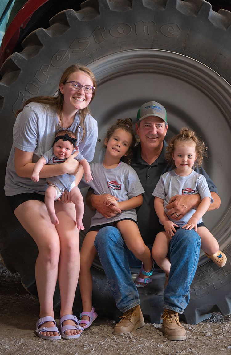 Smiling family sitting in a tractor tyre.